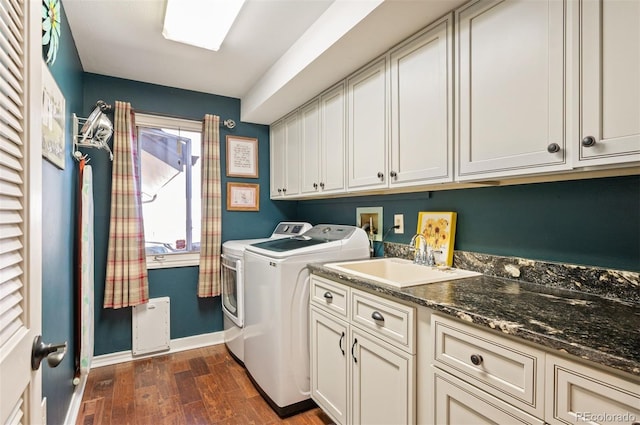 laundry area featuring dark wood-type flooring, cabinets, washer and clothes dryer, and sink