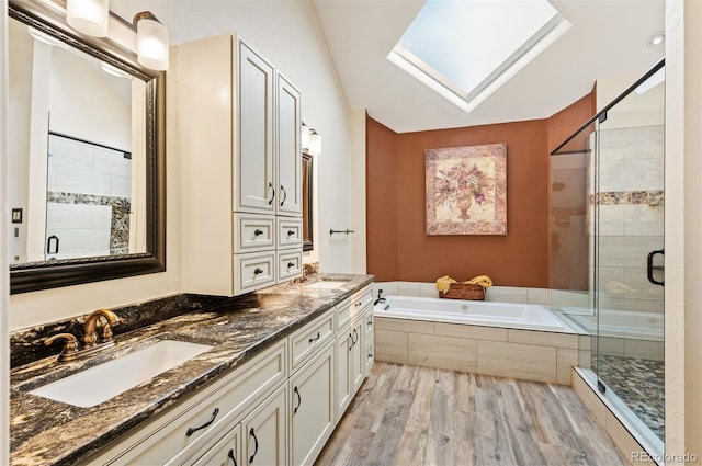 bathroom with hardwood / wood-style flooring, plus walk in shower, lofted ceiling with skylight, and vanity