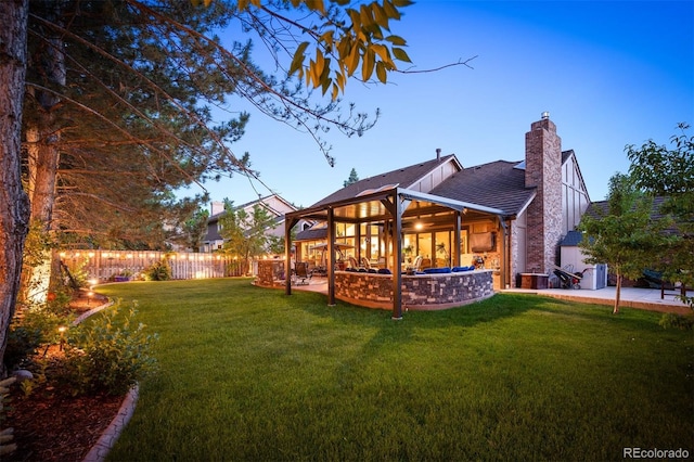 back house at dusk with a lawn and a patio