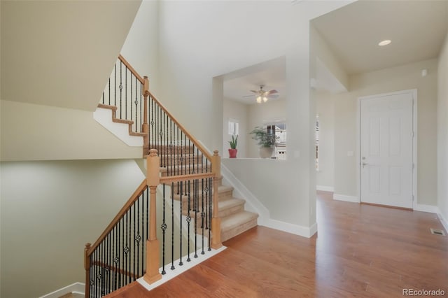 stairs featuring wood-type flooring and ceiling fan