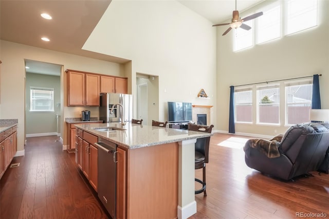 kitchen with dark hardwood / wood-style floors, an island with sink, sink, and a breakfast bar