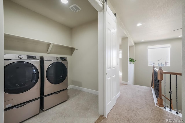 laundry area featuring a barn door, light carpet, and washer and dryer