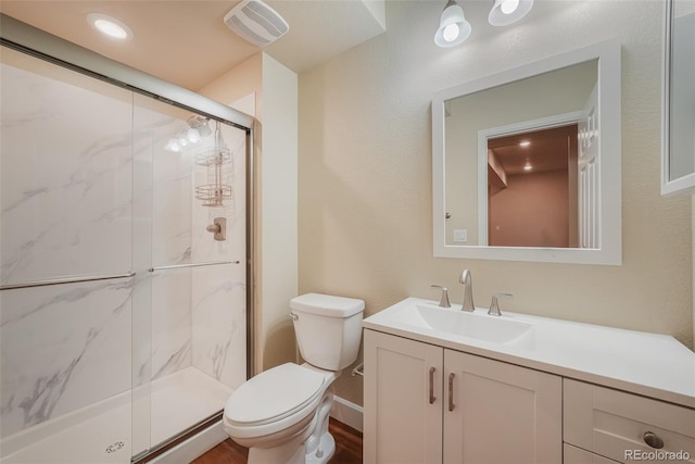 bathroom with vanity, a shower with door, and toilet