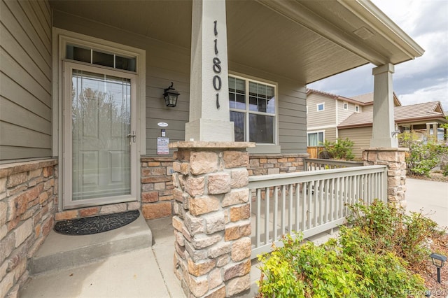 view of exterior entry with a porch and stone siding