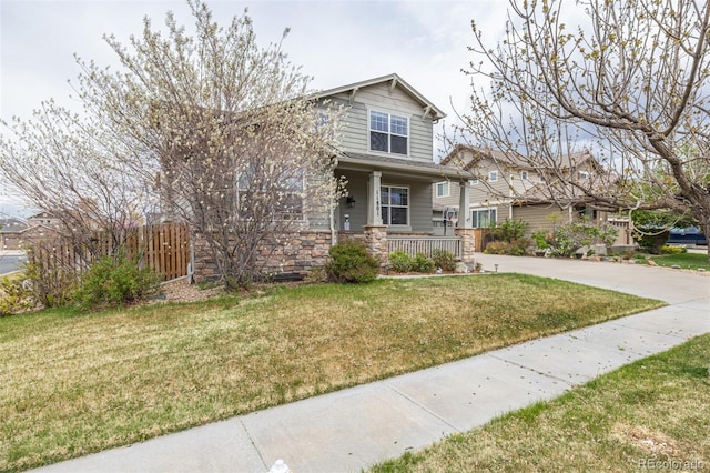 craftsman-style home with a porch, fence, stone siding, and a front yard