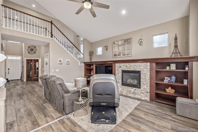living area featuring a ceiling fan, a fireplace, wood finished floors, high vaulted ceiling, and recessed lighting