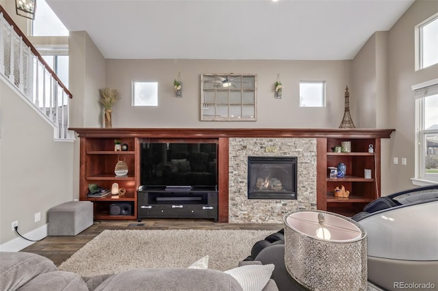 living room with stairs, baseboards, a glass covered fireplace, and wood finished floors