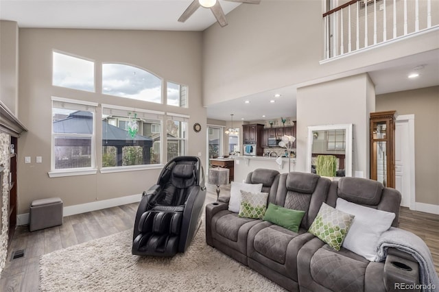living room featuring a ceiling fan, high vaulted ceiling, and light wood-style flooring