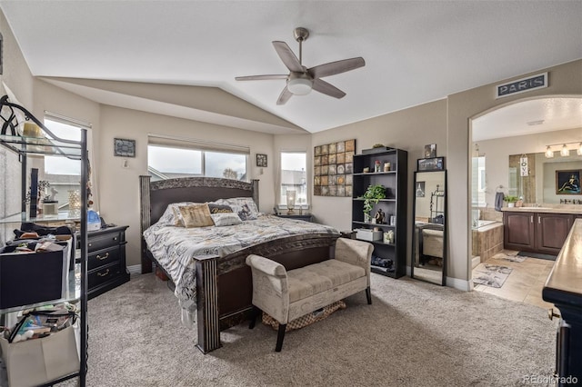 bedroom with connected bathroom, multiple windows, lofted ceiling, and light carpet