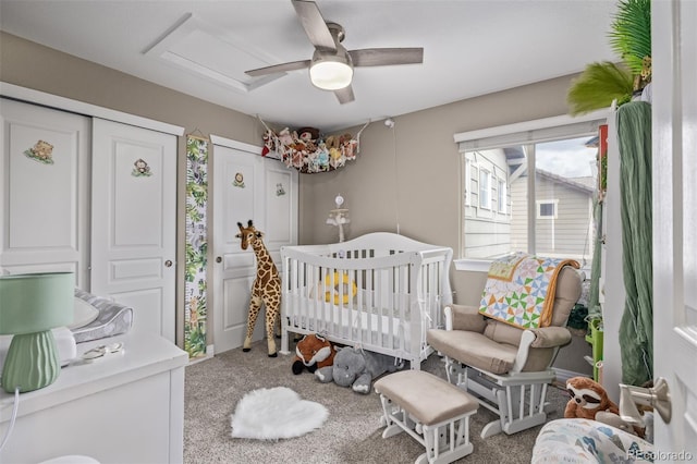 bedroom featuring a nursery area, ceiling fan, and carpet flooring