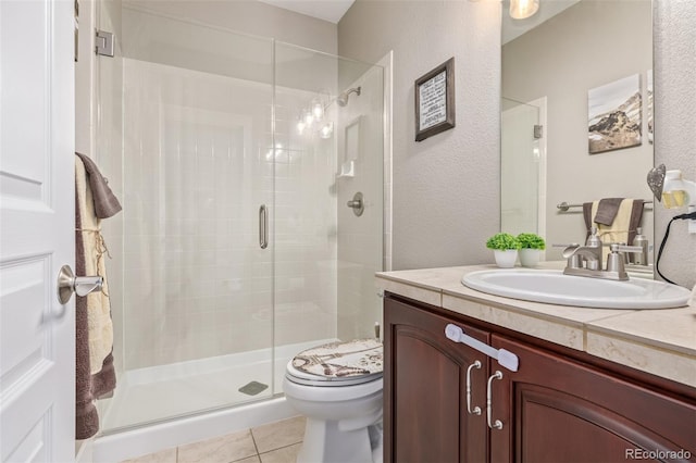full bathroom featuring vanity, a textured wall, a stall shower, and toilet