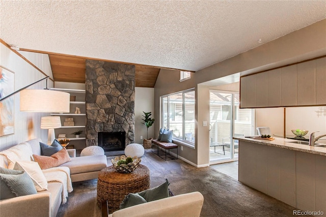 carpeted living room with lofted ceiling, sink, wood ceiling, a textured ceiling, and a stone fireplace