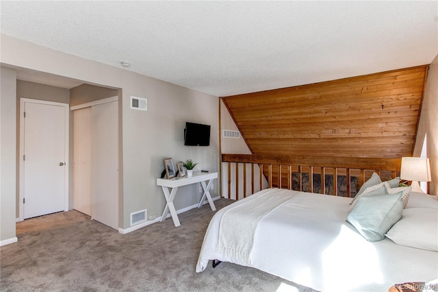 carpeted bedroom with lofted ceiling, a textured ceiling, and a closet