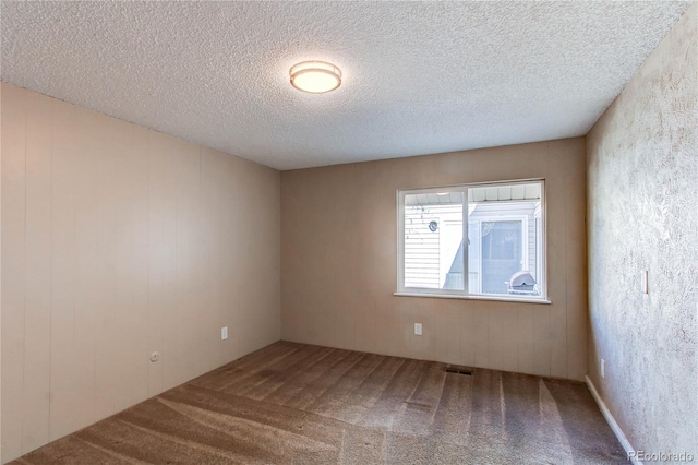 spare room with a textured ceiling and carpet flooring