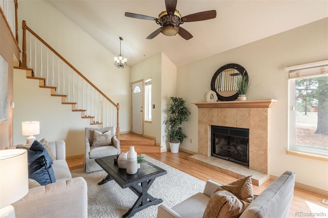 37677 Sable Ridge Rd, Elizabeth, CO 80107 - living room featuring wood finished floors, stairway, a tiled fireplace, a ceiling fan, and high vaulted ceiling