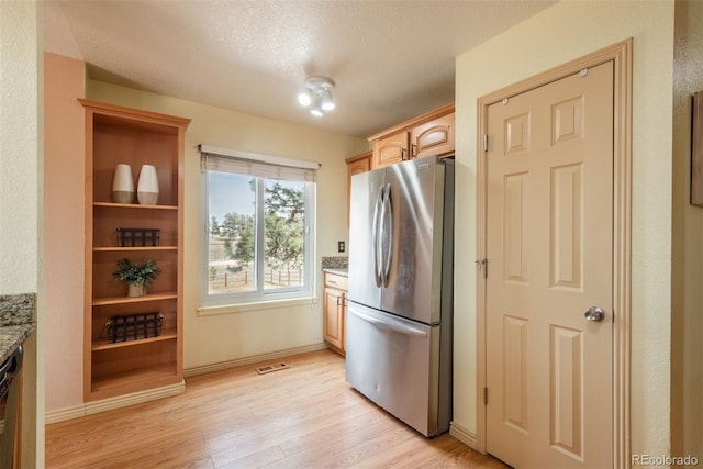 37677 Sable Ridge Rd, Elizabeth, CO 80107 - kitchen featuring freestanding refrigerator, light wood-type flooring, light stone counters, baseboards, and a textured ceiling