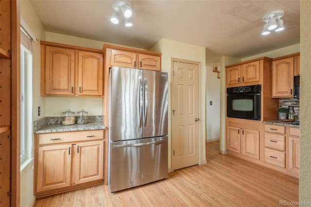 37677 Sable Ridge Rd, Elizabeth, CO 80107 - kitchen with freestanding refrigerator, black oven, light wood-type flooring, light stone counters, and baseboards