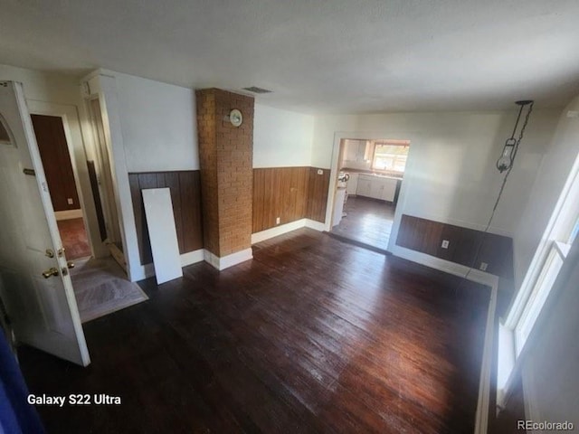 unfurnished living room featuring dark wood-type flooring and wooden walls