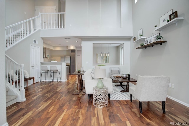 sitting room featuring wood-type flooring and a towering ceiling