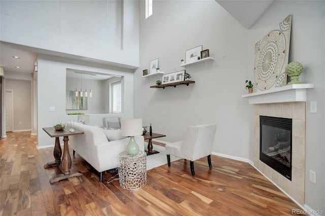 living room featuring a fireplace, wood-type flooring, and a high ceiling