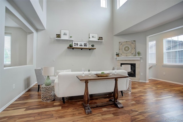 interior space featuring a fireplace, a towering ceiling, hardwood / wood-style flooring, and plenty of natural light