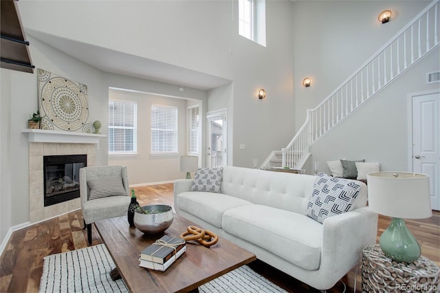 living room with a tile fireplace, hardwood / wood-style floors, and a high ceiling