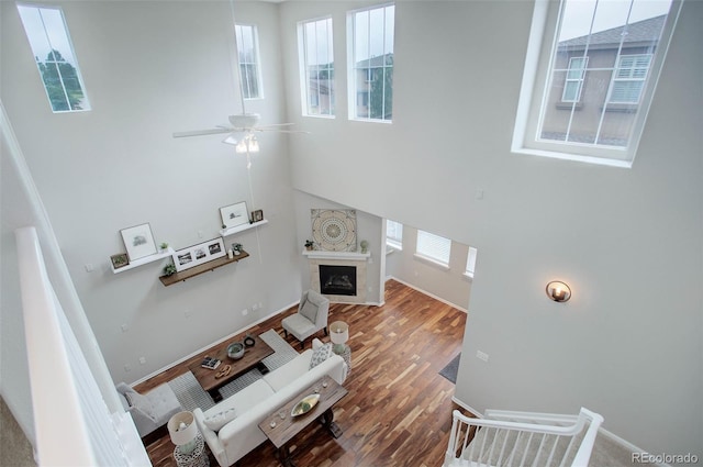 living room featuring ceiling fan, a high ceiling, and hardwood / wood-style flooring