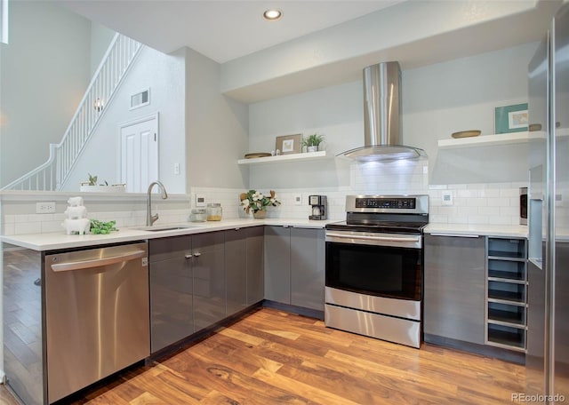 kitchen featuring appliances with stainless steel finishes, backsplash, gray cabinetry, sink, and exhaust hood