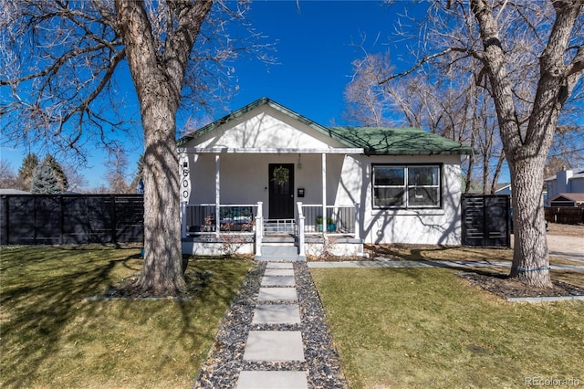 bungalow-style home featuring covered porch, fence, and a front yard