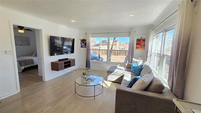 living area with recessed lighting, baseboards, a textured ceiling, and light wood finished floors