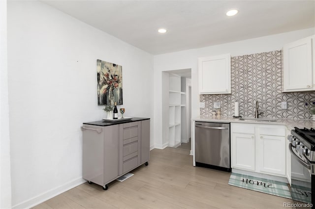 kitchen featuring tasteful backsplash, white cabinets, dishwasher, range with gas cooktop, and a sink