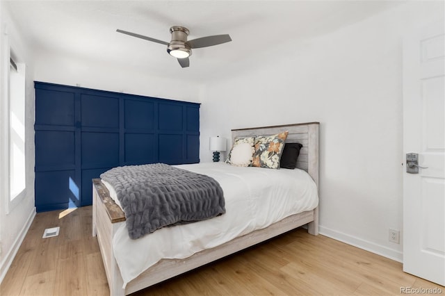 bedroom with light wood finished floors, baseboards, visible vents, and ceiling fan