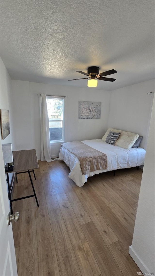 bedroom featuring ceiling fan, a textured ceiling, and hardwood / wood-style flooring