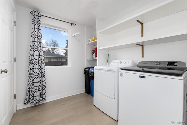 washroom featuring laundry area, baseboards, light wood finished floors, and washing machine and clothes dryer