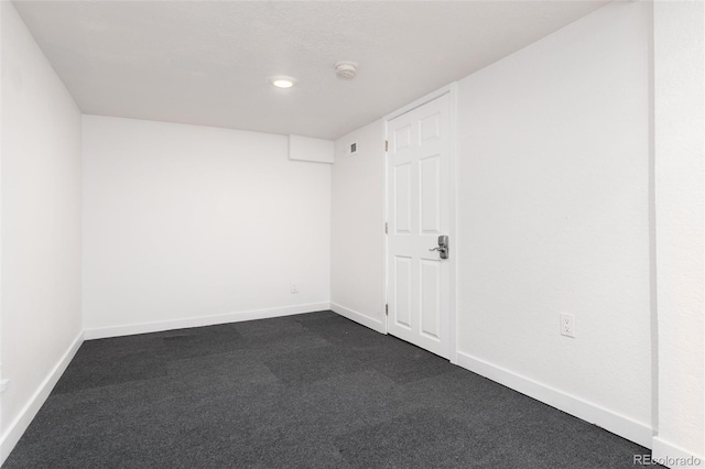 empty room with baseboards and dark colored carpet