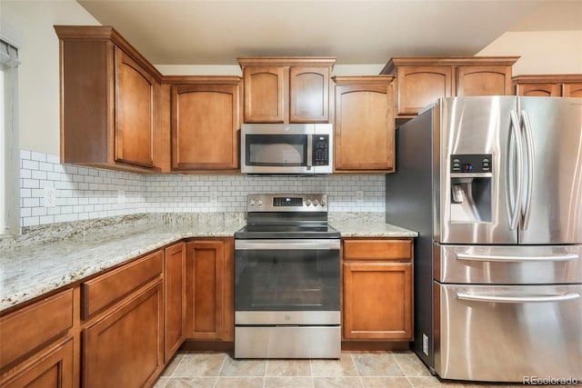 6349 Shooting Iron Way, Colorado Springs, CO 80923 - kitchen with stainless steel appliances, light stone counters, decorative backsplash, and brown cabinetry