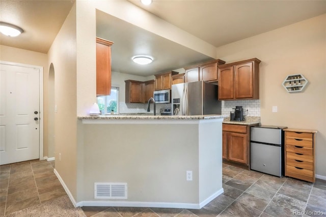 6349 Shooting Iron Way, Colorado Springs, CO 80923 - kitchen with stainless steel appliances, tasteful backsplash, stone finish floors, and arched walkways
