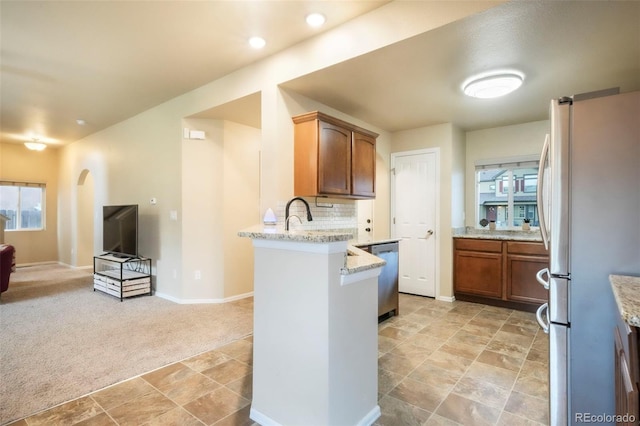 6349 Shooting Iron Way, Colorado Springs, CO 80923 - kitchen with stainless steel appliances, open floor plan, a peninsula, light colored carpet, and backsplash