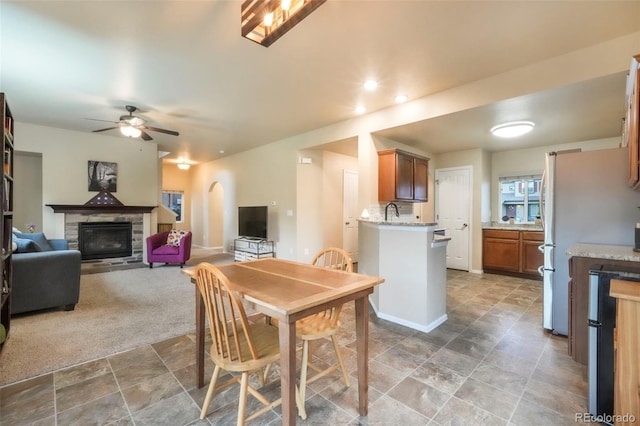 6349 Shooting Iron Way, Colorado Springs, CO 80923 - dining space featuring ceiling fan, stone finish floors, a glass covered fireplace, and arched walkways