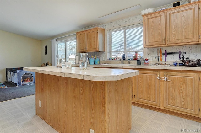 kitchen featuring backsplash, light brown cabinetry, sink, and a kitchen island