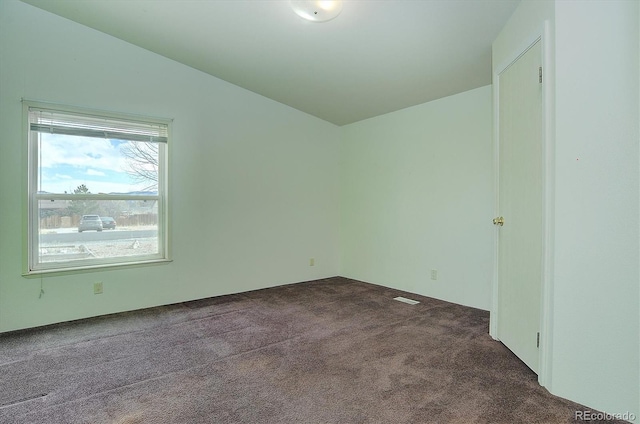 unfurnished room featuring dark colored carpet and lofted ceiling