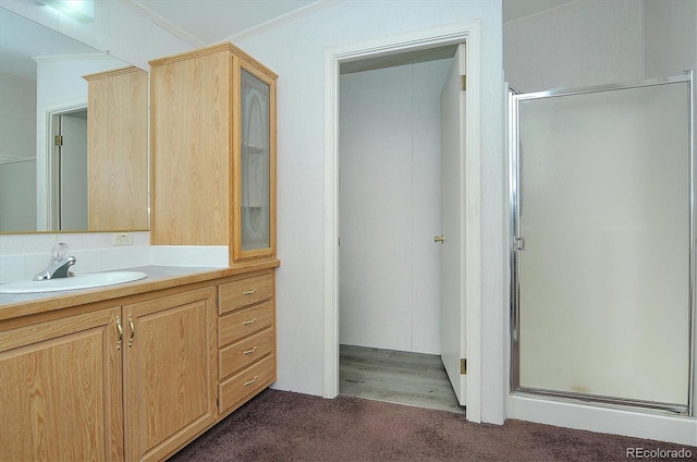 bathroom with hardwood / wood-style floors, vanity, a shower with shower door, and ornamental molding