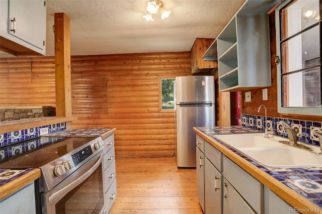 184 Signal Rock Rd, Golden, CO 80403 - kitchen featuring stainless steel appliances, log walls, light wood-type flooring, white cabinets, and a textured ceiling