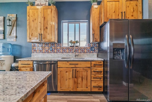 kitchen with light stone countertops, sink, dark wood-type flooring, stainless steel appliances, and decorative backsplash