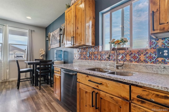 kitchen with a textured ceiling, stainless steel dishwasher, a healthy amount of sunlight, and sink