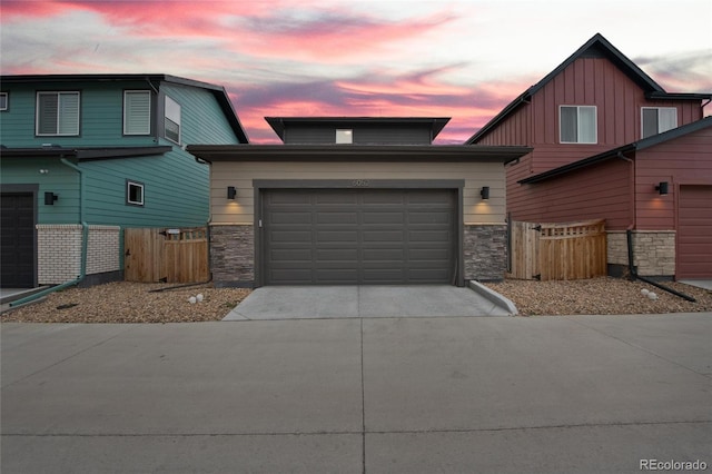 6052 N Malta St, Aurora, CO 80019 - view of front facade with stone siding, concrete driveway, a garage, and fence