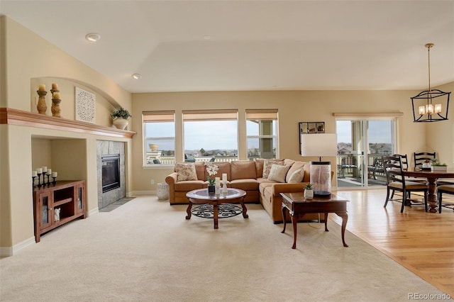 15004 Verbena St, Thornton, CO 80602 - living area with baseboards, a tile fireplace, light wood-style floors, a notable chandelier, and light colored carpet