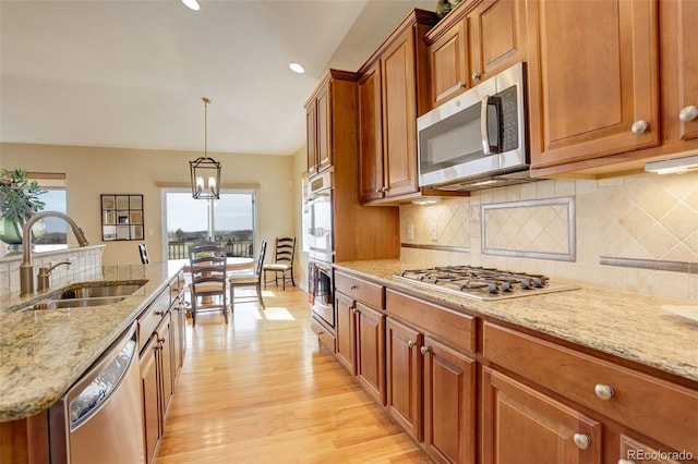 15004 Verbena St, Thornton, CO 80602 - kitchen with backsplash, light wood-style flooring, appliances with stainless steel finishes, brown cabinetry, and a sink