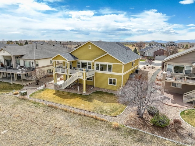 back of property featuring a yard, a shingled roof, stairs, a deck, and a residential view