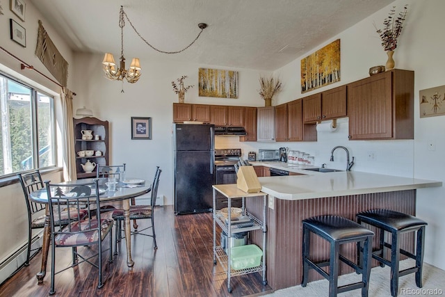 9800 Ryan Gulch Rd Unit A-101, Silverthorne, CO 80498 - kitchen featuring black appliances, under cabinet range hood, a peninsula, dark wood-type flooring, and a breakfast bar